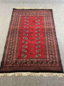 Carpet, Bokhara with repeating gul medallions on a burgundy field within stylised borders. L.188 W.