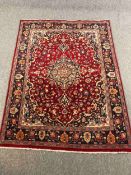A Persian carpet with flowerhead motifs across the field within naturalistic foliate borders. L.