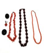 Two coral necklaces along with two carved jet brooches (one pin missing) and an earl;y cherry