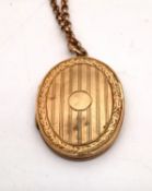 A 9ct yellow gold engraved locket and rolo link chain. The front and back of the locket engraved