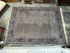 A Persian carpet with repeating geometric stylised flowerhead motifs across the filed within