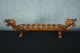 A hardwood decorative Mancala board game in the shape of a dragon. With carved decoration and