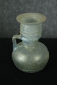 A Roman iridescent glass oil jug. H.12cm.