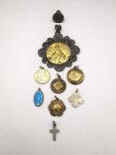 A collection of religious medallions, including a filigree wirework medallion of Mary and Jesus, a