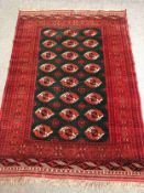 A Bokhara carpet with repeating gul motifs across the field within broad multiple stylised