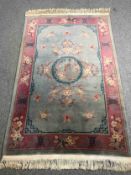 A Chinese woollen carpet with central flowerhead medallion within complementary burgundy borders.