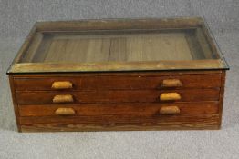 A 1920's pine planners chest, with later glass top to form a coffee table. H.40 W.123 D.92cm.
