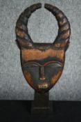 † A carved African tribal ceremonial mask with twisted horns. H.37cm.