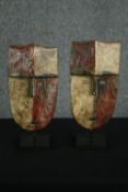 † A pair of carved and painted Africans Duma tribal masks on display stands. H.40cm. (each).