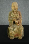 † A 19th century Chinese carved and painted figure of a seated monk in traditional robes. H.52cm.