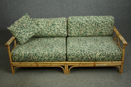 A mid 20th century retro bamboo settee, with leaf patterned upholstery. H.70 W.168 D.87cm.