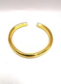 A yellow metal (tests as 22ct yellow gold) solid bangle with raised foliate design. Aperture