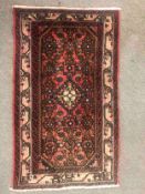 A 20th century Hamadan rug with red ground and a central medallion. L.118 W.69cm.