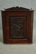 A George II oak hanging corner cupboard, with later Victorian carving. H.64 W.53 D.30cm.