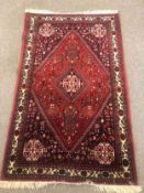 A 20th century Qashqai style rug with a deep red ground. L.155 W.97cm.