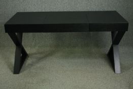 A late 20th century ebonized desk with hinged central section on X frame supports. H.76 W.160 D.