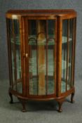 An Art Deco walnut and glass bow-fronted display cabinet, enclosing glass shelves. H.115 W.80 D.