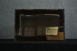 A 1970's glass and tinted glass wall mirror with a central shaped bevelled plate. H.47 W.72cm.
