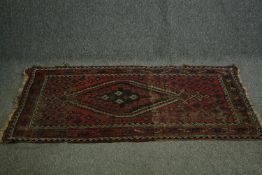 A Persian Quasgai rug with central diamond medallion on a burgundy ground. L.148 W.100cm.