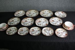 A group of Japanese Satsuma porcelain plates and a pair of tea cups and saucers. Dia.21cm. (