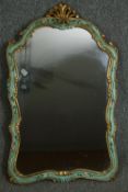 A carved and painted 19th century Rococo style continental parcel gilt shaped wall mirror. H.84 W.