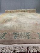 A large woollen carpet with allover Chinese motifs on a taupe field within stylised borders,