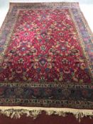 A mid 20th century Tabriz style carpet with a raspberry red field and allover floral design. L.355