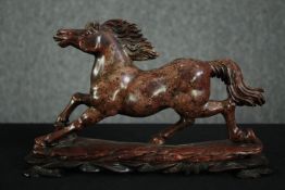 A carved soapstone figure of a running horse on a carved hardwood stand. H.18 W.30 D.9cm.