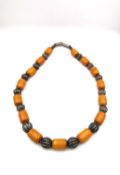 An amber plastic and white metal cylindrical beaded statement necklace. L.54cm