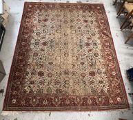 An Afghan carpet with scrolling foliate design on a biscuit ground with naturalistic multiple