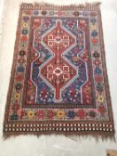 A Kazak rug with double hooked medallions on a flowerhead pale blue ground within stylised