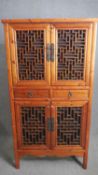 A Chinese hall cabinet with lattice panelled doors and fitted with frieze drawers on block supports.
