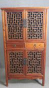 A Chinese hall cabinet with lattice panelled doors and fitted with frieze drawers on block supports.