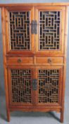 A Chinese hall cabinet with lattice panelled doors and fitted with frieze drawers on block supports.