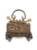 A Tibetan leather tinder pouch with a hand forged iron handle attached to a pair of engraved brass