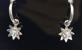 A pair of 9k white gold star shaped earrings inset with lab grown diamonds on curved bars along with