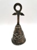 A Central or South American style cast white metal bell with shaped handle above a stylised