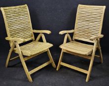 A pair of weathered teak folding garden armchairs.