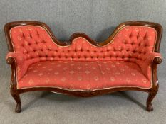 A Victorian style mahogany sofa in carved frame and deep buttoned upholstery. H.89 W.189 D.77cm