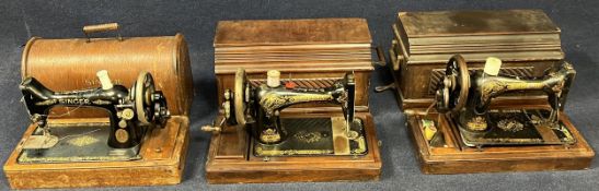 A collection of three vintage Singer sewing machines.