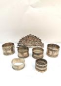A collection of six silver napkin rings and a German pierced letter holder with figural design
