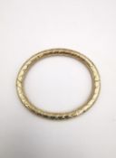A modern Pobjoy mint 9 carat yellow gold bangle with criss-cross design. Opens with hidden push