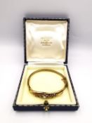 A Victorian 15 carat yellow gold and seed pearl floral design bangle, set with nineteen round seed