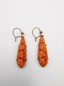 A pair of antique yellow metal (tests higher than 9ct) carved and pierced orange coral drop earrings