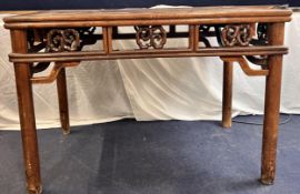 A Chinese carved hardwood centre table on circular section supports. H.80 W.116 D.70cm