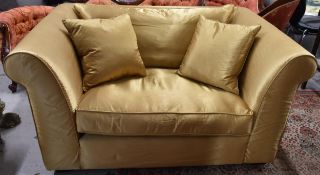 A large armchair or loveseat upholstered in gold satin. H.72 W.145 D.95cm