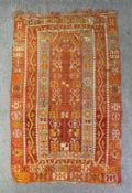 A kelim carpet with repeating stylised flowerhead motifs across a terracotta field. L.231 W.142cm