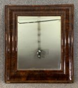 A wall mirror in oyster veneered cushion frame with original bevelled plate. H.89 W.78cm