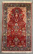 A Persian rug with scrolling foliate detail on a burgundy field within naturalistic multiple
