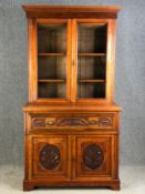 A late 19th century carved walnut two section library bookcase with fitted secretaire drawer. H.